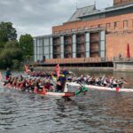 Two dragon boat teams racing on a river at a Hook Norton Vets charity team event